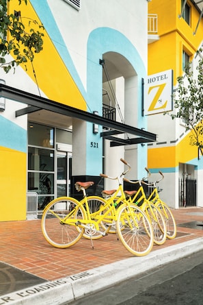 A yellow bicycle parked in front of a building with a sign reading 'Hotel Z' and the number '521' on the facade.