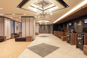 A modern hotel lobby with a central seating area, a reception desk, and a large chandelier. - Dormy Inn Kawasaki (KAWASAKI SHI)