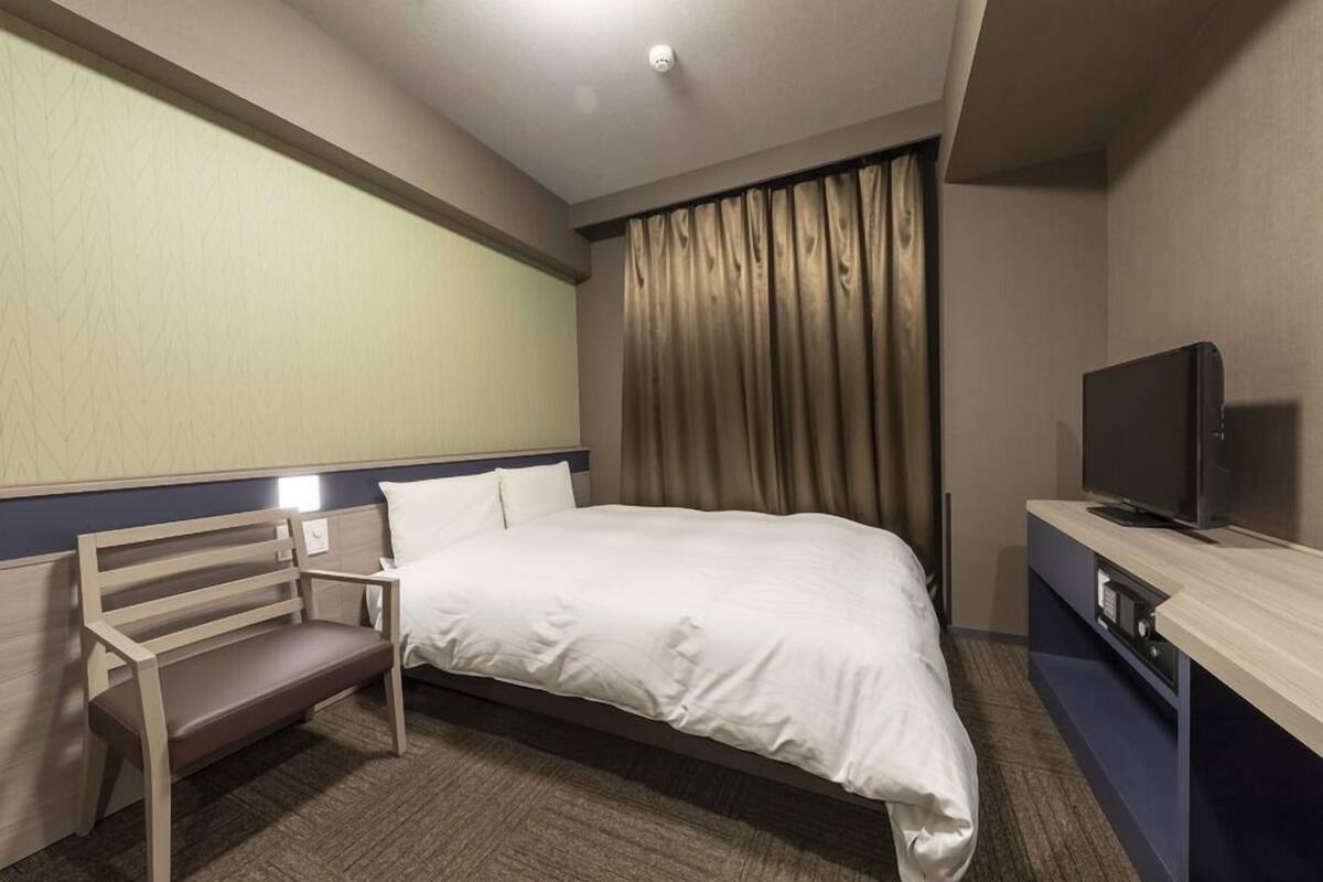 Une chambre d’hôtel avec un lit, une télévision, un bureau et un banc.