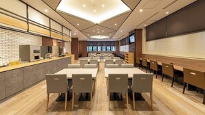 A modern conference room with a long table, chairs, a coffee station, and a large screen.