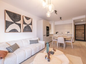 A modern living room with a sofa, a coffee table, and abstract wall art. - Apartment in the heart of the Alps - 4 guests (Huez)