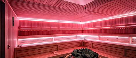A sauna with wooden benches and a central fire pit.