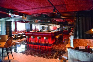 Een bar met krukken, een toog en een zithoek met tafels en stoelen.