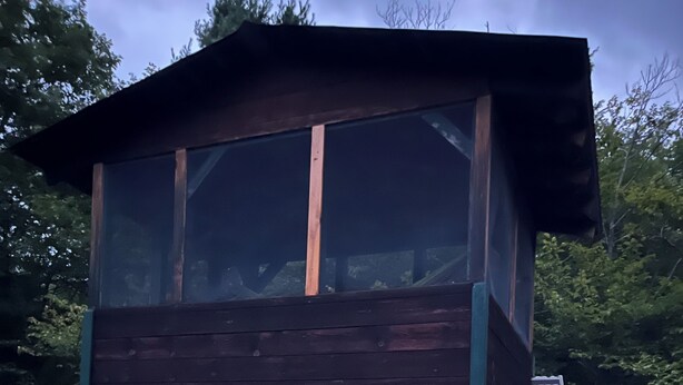 A two-story wooden cabin with a visible interior, a window, and a door.