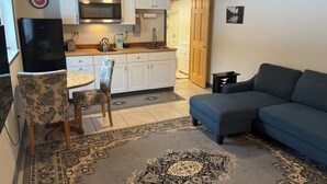 A compact living space with a kitchenette, a dining area, a sofa, and a patterned rug.