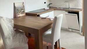 Une cuisine moderne avec des meubles blancs, une table à manger en bois et une vue sur l’extérieur.