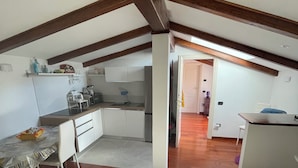 Une cuisine moderne avec des meubles blancs, un coin repas comprenant une table et des chaises, et un plafond en bois.