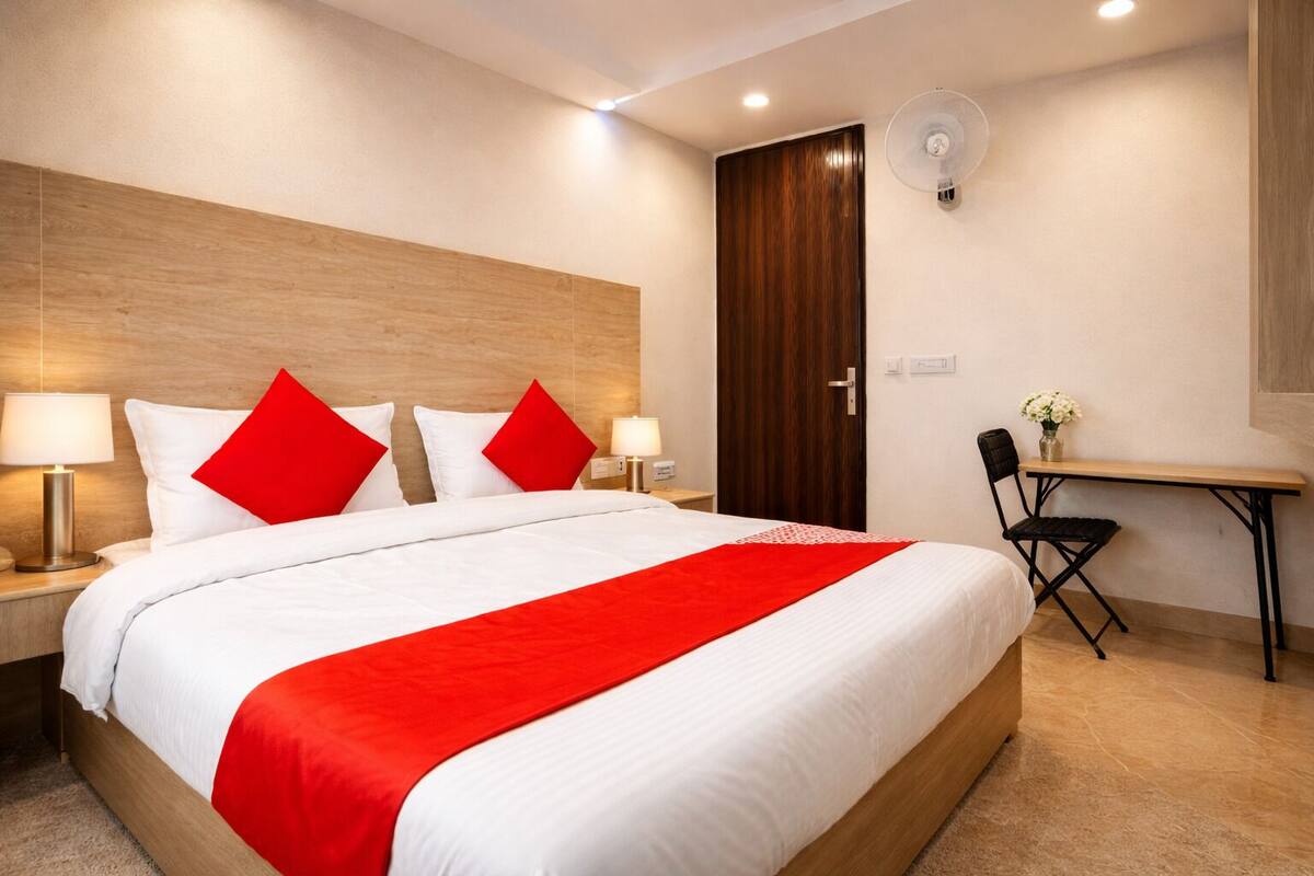 Une chambre d’hôtel avec un grand lit, des lampes de chevet, un bureau avec une chaise et une armoire en bois.