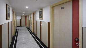 A hotel corridor with doors, framed artwork, and a tiled floor. - Hotel Vindhya Inn - Delhi Airport (New Delhi)