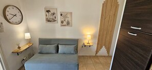 A bedroom with a bed, a wall clock, two wall-mounted lamps, and a wooden wardrobe. - T2 terrace & pool 100m from the beach (Linguizzetta)