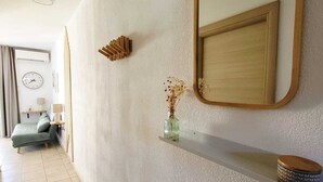 Ein Flur mit einem Bett, einer Uhr, einem Spiegel und einem Regal mit einer Vase.