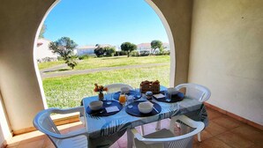 Ein Tisch mit Tellern, Gläsern und einem Brotkorb, mit Blick auf eine Wiese mit Bäumen und Gebäuden.