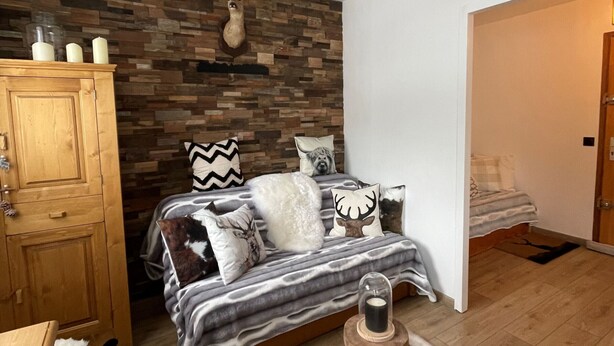 Un dormitorio con cama, armario de madera y pared de piedra.