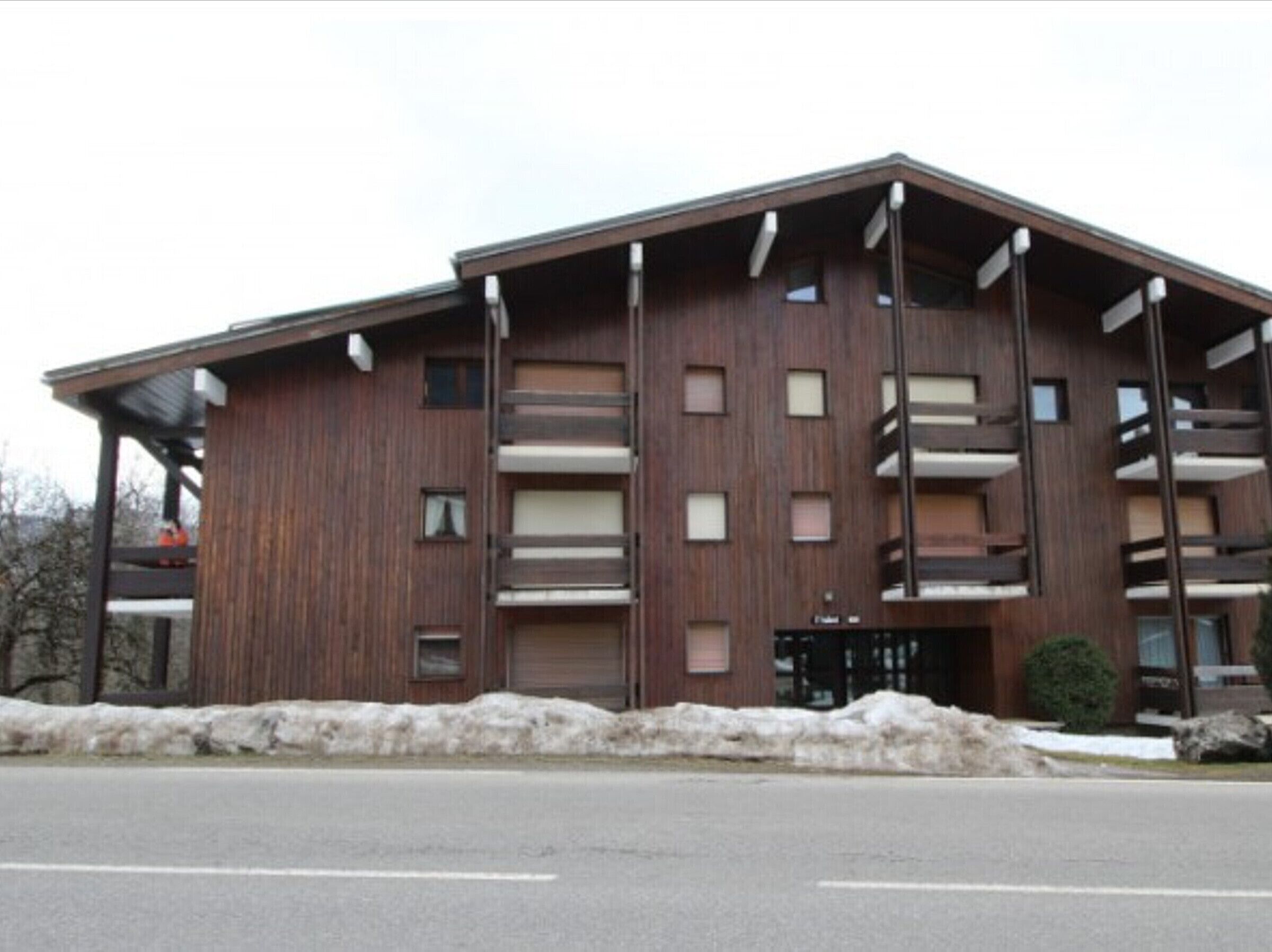 A multi-story building with a wooden facade, balconies, and a garage entrance.