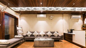 A reception area with a sofa, a glass-top coffee table, and a reception desk. - Townhouse Kota Airport (Kota)