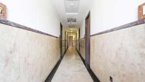 A long, narrow hallway with marble walls and a polished floor, leading to a door at the end. - Townhouse Kota Airport (Kota)