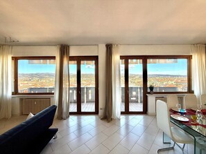 A room with a city view, a dining table with chairs, and a sofa. - 160 sqm apartment with a spectacular 180° view of Verona (Verona)