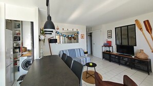 A living room with a sofa, TV, and two wooden paddles on the wall. - Stunning T2 sea view - 4 guests (Canet-en-Roussillon)