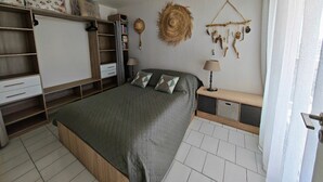 A bedroom with a bed, bedside table, lamp, wardrobe, and wall decorations. - Stunning T2 sea view - 4 guests (Canet-en-Roussillon)