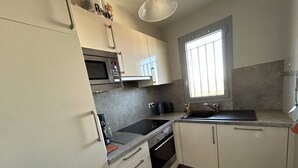A compact kitchen with a microwave, stove, sink, and cabinets. - Sea view apartment, private parking - 4 guests (Argelès-sur-Mer)