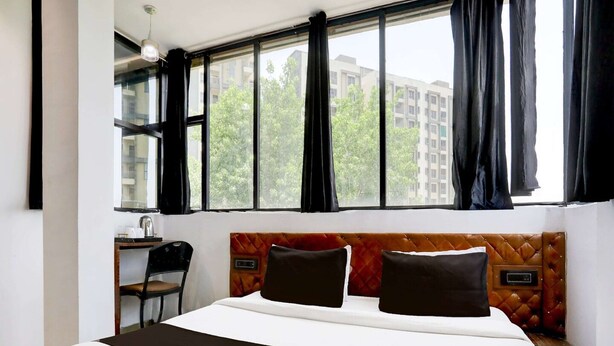 A hotel room with a large bed, a desk, and a chair. - Deluxe Easy Stay (Bhopal)