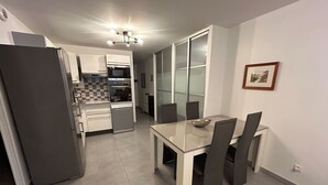 Una cocina moderna con comedor, que incluye refrigerador, horno, microondas y una mesa de comedor con sillas.