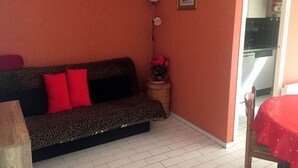 Un petit salon avec un canapé, une table, une lampe et un tableau au mur.