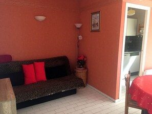 A small living area with a sofa, a table, a lamp, and a picture on the wall. - Cozy apartment with AC - 4 guests, near the beach (Argelès-sur-Mer)