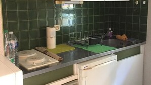 Une cuisine avec des carreaux verts, un rouleau d’essuie-tout, une bouteille d’eau et un égouttoir à vaisselle.