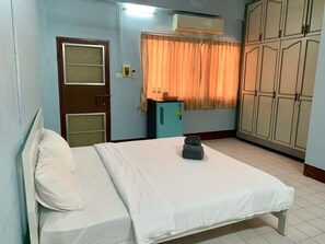 A room with a bed, a wardrobe, a small cabinet, and a window with curtains.