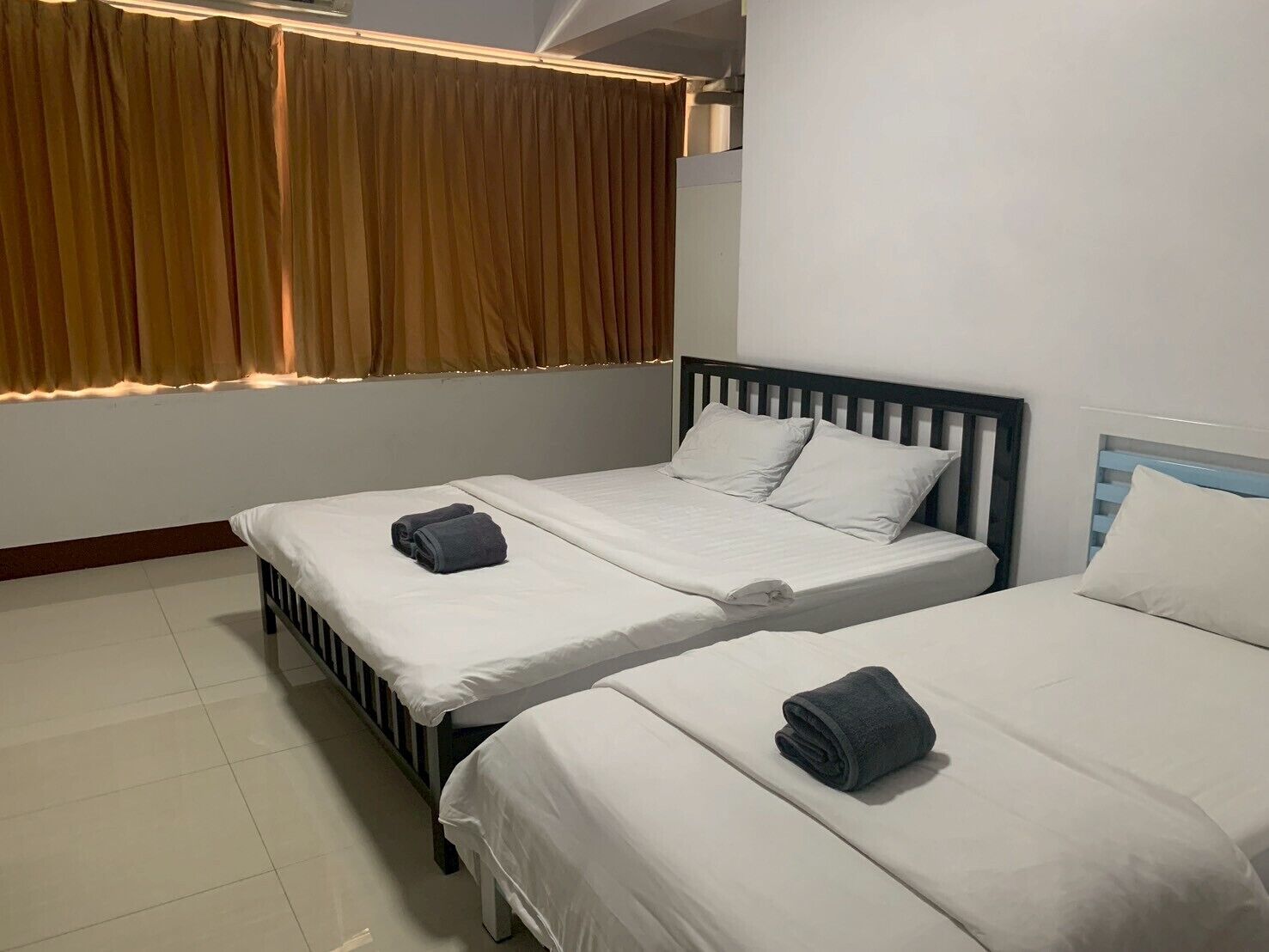 A hotel room with two beds, a window with curtains, and a white wall.