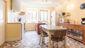 A compact kitchen with a dining table, chairs, a refrigerator, a microwave, and a clock on the wall. - Cozy group cottage in Bucey-lès-Gy, perfect for hikers (Bucey-lès-Gy)