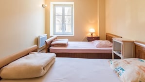 A bedroom with two beds, a window, a bedside lamp, and a small table. - Cozy group cottage in Bucey-lès-Gy, perfect for hikers (Bucey-lès-Gy)