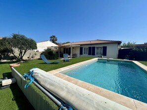 Ein Schwimmbad mit überdachtem Deck, einer Terrasse und einem Haus mit Ziegeldach.