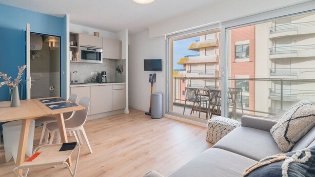 Un apartamento moderno con cocina, comedor y balcón con vistas a edificios.