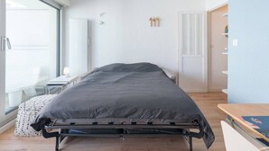 Un dormitorio moderno con una cama, una mesita de noche, una lámpara, una ventana y una puerta.