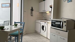 Eine kompakte Küche mit Waschmaschine, Mikrowelle und einer Essecke mit Stühlen.