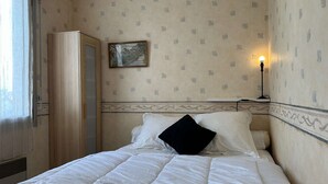 Ein Hotelzimmer mit einem Bett, einem Kleiderschrank, einem Bild an der Wand und einem Nachttisch mit Lampe.