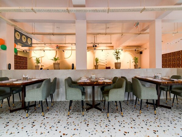 A restaurant interior with a long counter, green upholstered chairs, and a terrazzo floor. - Deluxe With Twin Bed Harika Inn (Srikakulam)