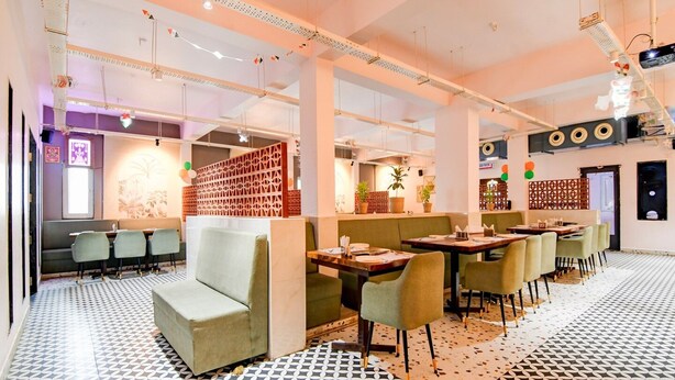 En restaurantindretning med højt til loftet, mønstret gulv og moderne møbler.