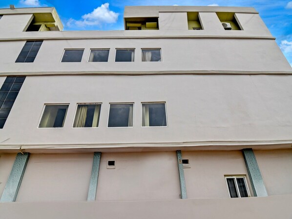 A multi-story building with a flat facade, rectangular windows, and a central vertical strip.