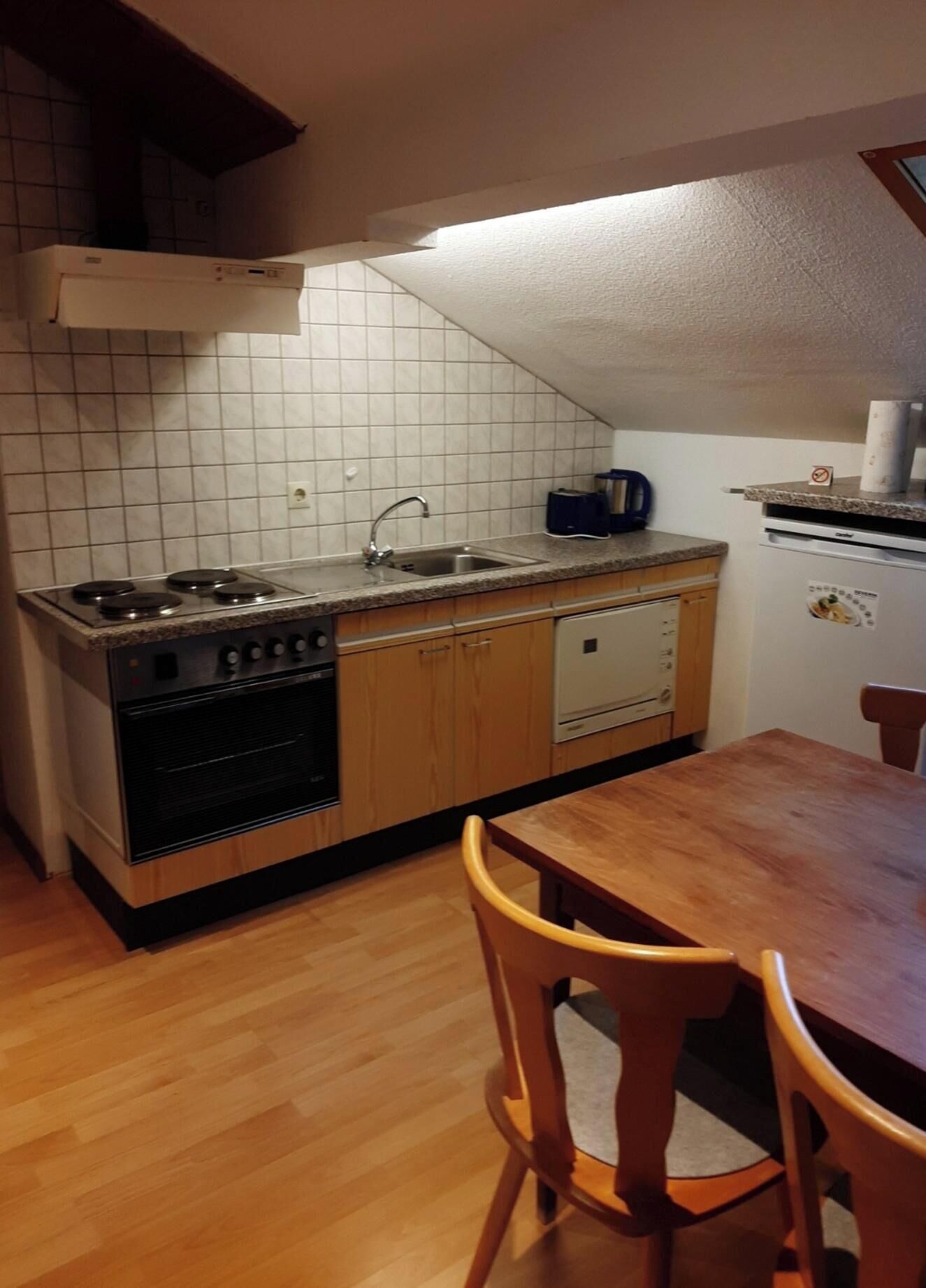 A kitchen with a stove, sink, and wooden cabinets.