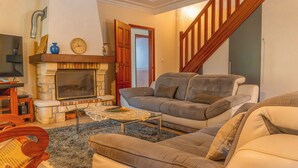A living room with a fireplace, a sofa, a coffee table, and a staircase.