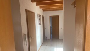 A hallway with wooden doors, tiled flooring, and a ceiling with exposed beams. - Vacation apartment Loder 108 m2 (Blumberg)