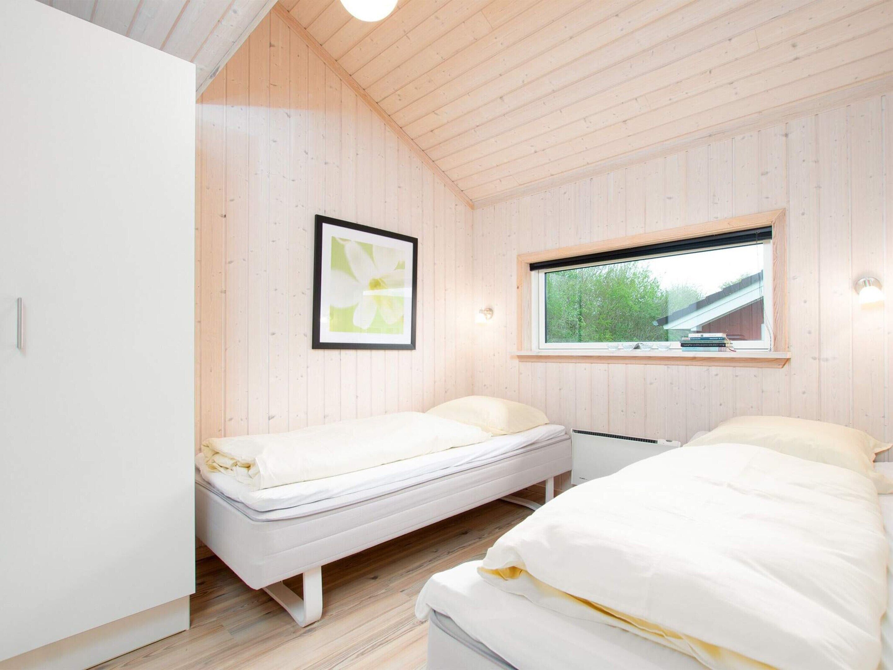 Une chambre avec deux lits simples, une fenêtre donnant sur un paysage verdoyant et un tableau encadré au mur.