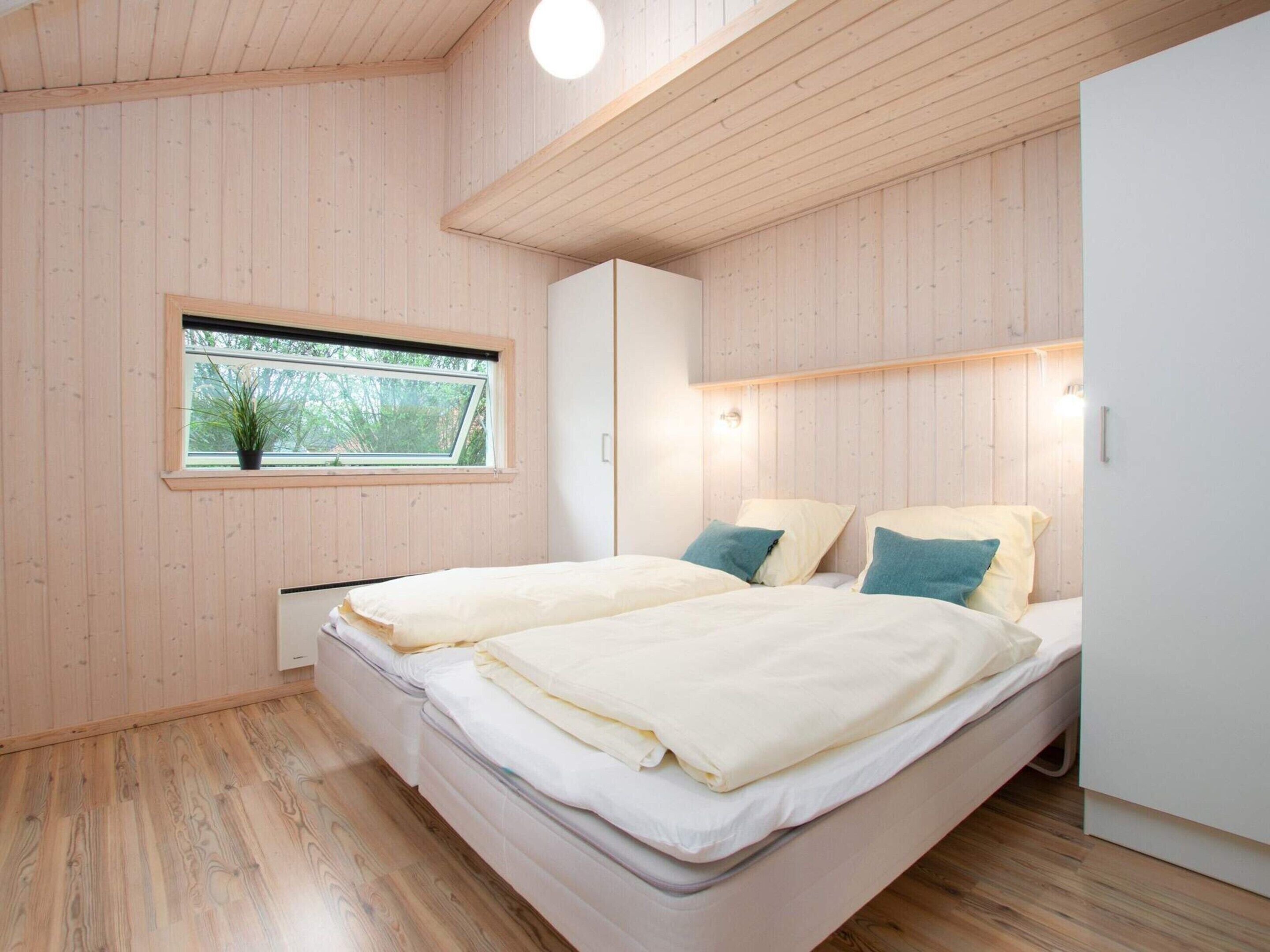 Un dormitorio con cama, ventana con vistas, paredes de madera y una lámpara en el techo.
