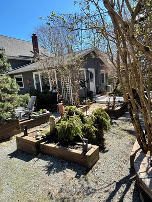 A residential property with a gravel driveway, wooden planters, and a small garden area. - Beech Hill Studio, Dogs and Children Friendly on lovely Mount Desert Island. (MOUNT DESERT)