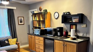 A compact kitchen with a microwave, toaster, coffee maker, and wooden cabinets.