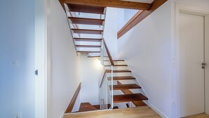 Eine Treppe mit Holzboden und weißen Geländern, die zu einer Tür führt.