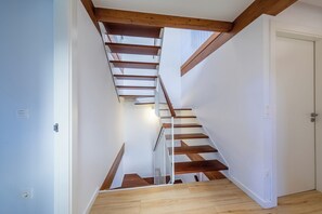 Eine Treppe mit Holzboden und weißen Geländern, die zu einer Tür führt.